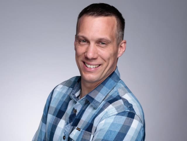 Porträtfoto von Daniel Marzinzik, zertifizierter Brandschutzdozent, im blau-karierten Hemd